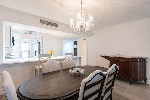 1150 Tarpon Center Dr Unit 1D, Venice, FL 34285 - dining room with crown molding, light wood-style floors, a chandelier, and a ceiling fan