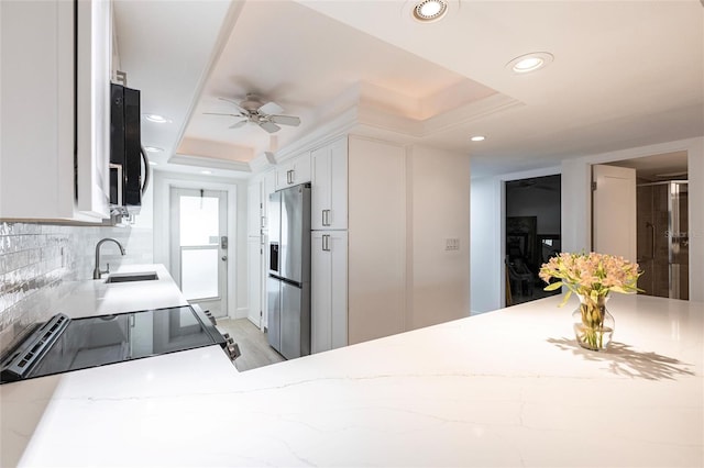 1150 Tarpon Center Dr Unit 1D, Venice, FL 34285 - kitchen with stainless steel refrigerator with ice dispenser, a raised ceiling, light stone countertops, white cabinetry, and decorative backsplash