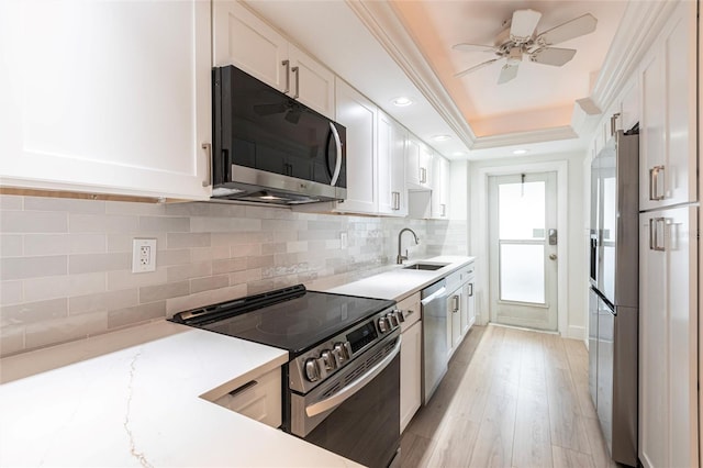 1150 Tarpon Center Dr Unit 1D, Venice, FL 34285 - kitchen with appliances with stainless steel finishes, white cabinets, decorative backsplash, a ceiling fan, and a tray ceiling