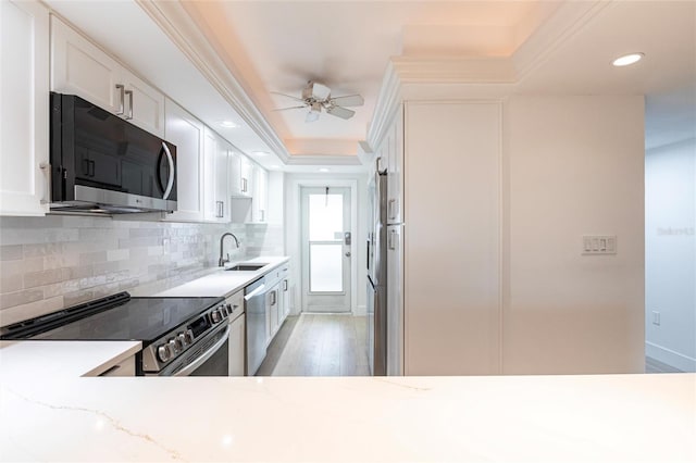1150 Tarpon Center Dr Unit 1D, Venice, FL 34285 - kitchen with appliances with stainless steel finishes, light stone counters, backsplash, white cabinetry, and ceiling fan