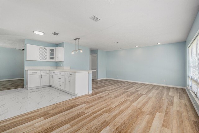 801 Lamont Pl, Temple Terrace, FL 33617 - kitchen featuring a peninsula, white cabinets, light countertops, glass insert cabinets, and pendant lighting