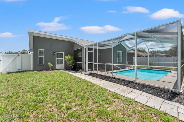 10032 Basin St, New Port Richey, FL 34655 - rear view of property featuring a fenced backyard, a gate, stucco siding, a patio area, and glass enclosure
