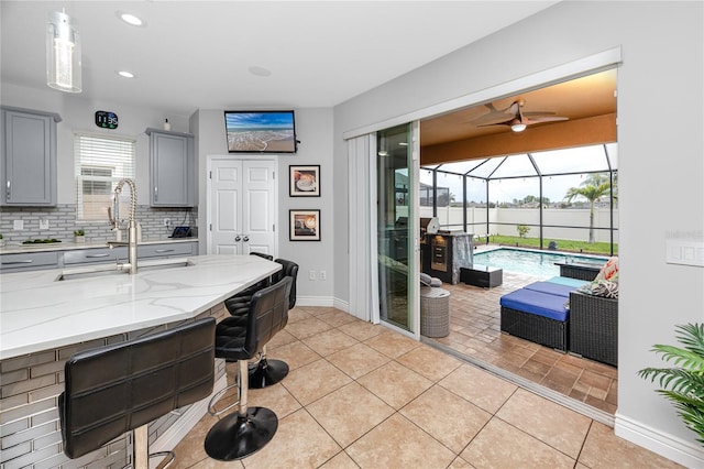 1601 Fox Grape Loop, Lutz, FL 33558 - kitchen with gray cabinetry, a sunroom, ceiling fan, a kitchen breakfast bar, and tasteful backsplash