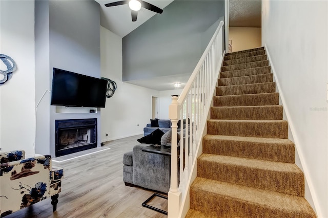 7320 Hideaway Trl, New Port Richey, FL 34655 - stairs featuring wood finished floors, a ceiling fan, a fireplace, and a towering ceiling