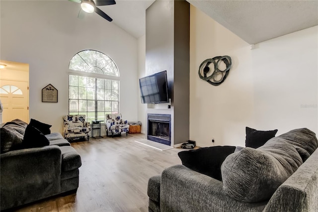 7320 Hideaway Trl, New Port Richey, FL 34655 - living room featuring high vaulted ceiling, a fireplace with raised hearth, wood finished floors, and a ceiling fan