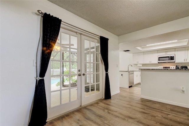 7320 Hideaway Trl, New Port Richey, FL 34655 - kitchen with appliances with stainless steel finishes, french doors, white cabinets, and a textured ceiling