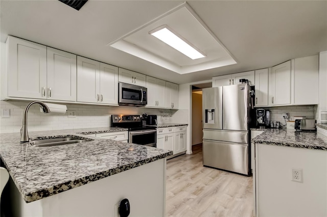 7320 Hideaway Trl, New Port Richey, FL 34655 - kitchen featuring stainless steel appliances, a tray ceiling, a peninsula, white cabinets, and tasteful backsplash