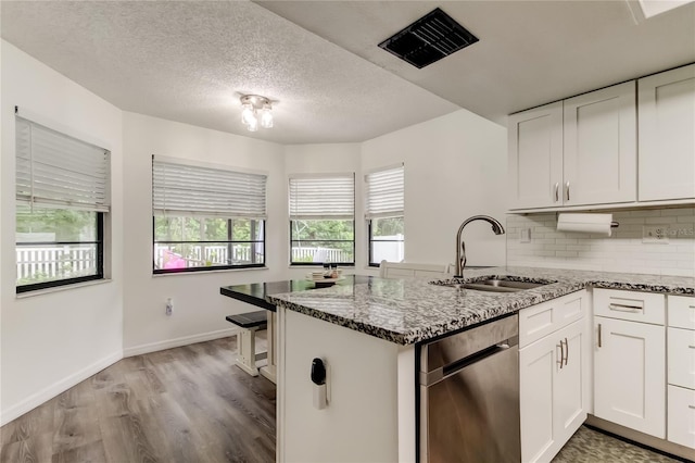7320 Hideaway Trl, New Port Richey, FL 34655 - kitchen with dishwasher, a peninsula, stone countertops, white cabinetry, and wood finished floors