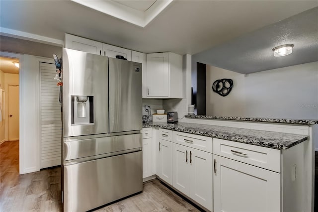 7320 Hideaway Trl, New Port Richey, FL 34655 - kitchen featuring stainless steel fridge with ice dispenser, a peninsula, white cabinetry, dark stone counters, and light wood-style floors