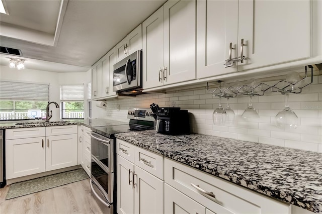 7320 Hideaway Trl, New Port Richey, FL 34655 - kitchen with appliances with stainless steel finishes, dark stone counters, white cabinets, and light wood-style flooring