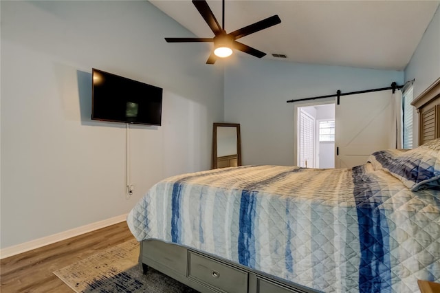 7320 Hideaway Trl, New Port Richey, FL 34655 - bedroom with wood finished floors, a barn door, a ceiling fan, and high vaulted ceiling