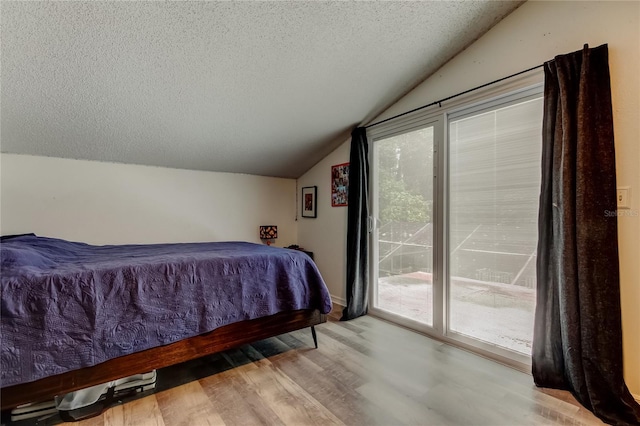 7320 Hideaway Trl, New Port Richey, FL 34655 - bedroom with vaulted ceiling, access to exterior, a textured ceiling, and wood finished floors