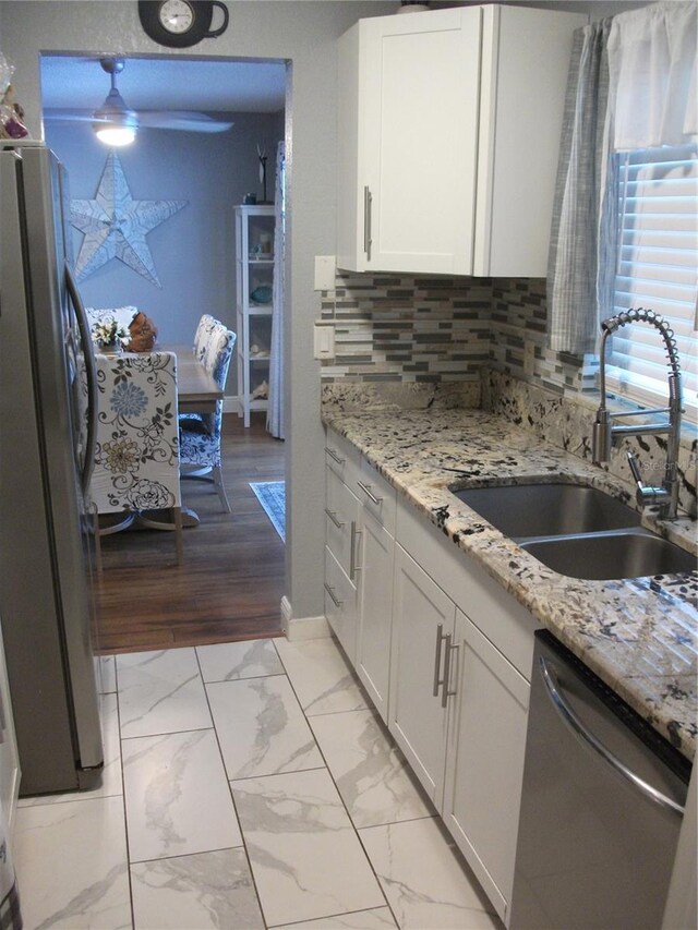 12411 Brookside St, Spring Hill, FL 34609 - kitchen with appliances with stainless steel finishes, white cabinetry, light marble finish flooring, ceiling fan, and tasteful backsplash