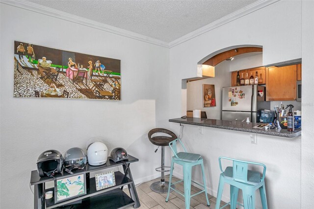 10195 Sailwinds Blvd N Unit 208, Largo, FL 33773 - kitchen featuring freestanding refrigerator, brown cabinetry, arched walkways, a textured ceiling, and ornamental molding