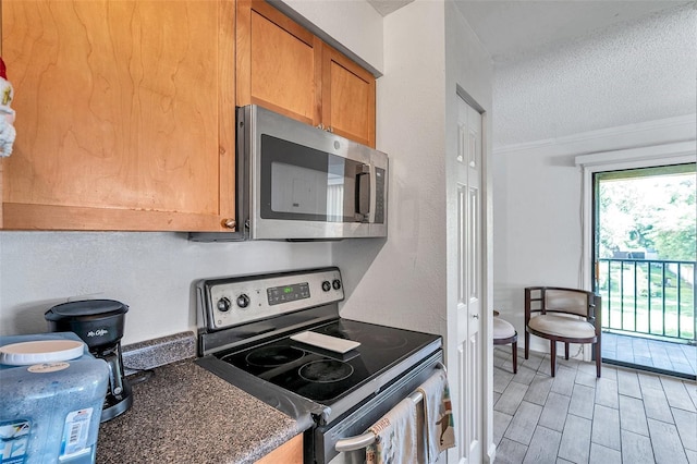 10195 Sailwinds Blvd N Unit 208, Largo, FL 33773 - kitchen with stainless steel appliances, a textured ceiling, ornamental molding, wood tiled floors, and dark countertops