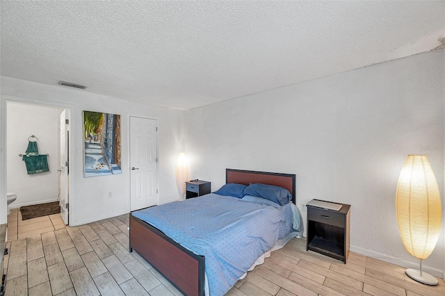 10195 Sailwinds Blvd N Unit 208, Largo, FL 33773 - bedroom featuring wood finish floors, a textured ceiling, and connected bathroom