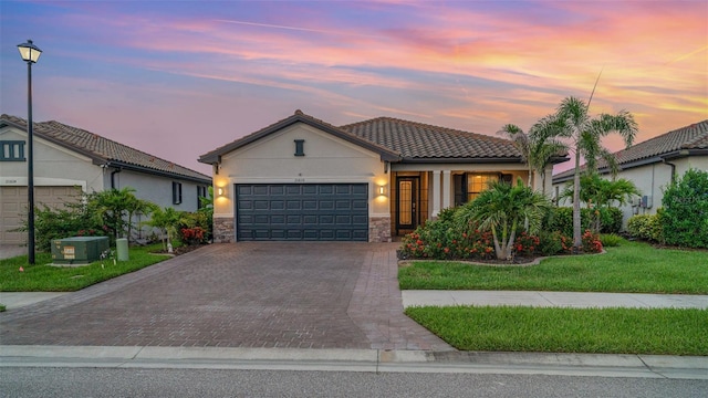 20828 Cattail Blvd, Venice, FL 34292 - view of front of house featuring an attached garage, stucco siding, decorative driveway, a front lawn, and a tile roof