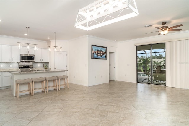 20828 Cattail Blvd, Venice, FL 34292 - kitchen featuring stainless steel appliances, decorative backsplash, crown molding, ceiling fan, and a kitchen breakfast bar