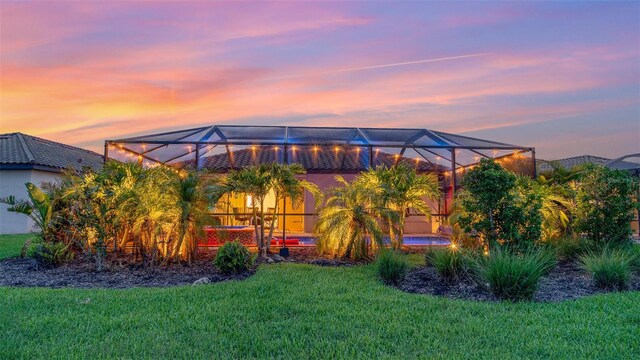 20828 Cattail Blvd, Venice, FL 34292 - back of house at dusk with glass enclosure and a lawn