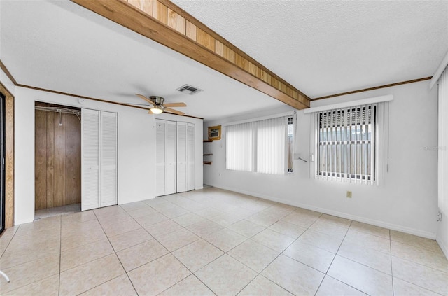 4143 Gray Squirrel Ln, New Port Richey, FL 34653 - unfurnished bedroom with multiple closets, light tile patterned flooring, a ceiling fan, and a textured ceiling