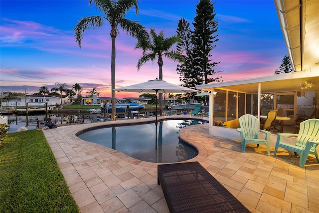 4252 Floramar Ter, New Port Richey, FL 34652 - pool at dusk with a patio area, boat lift, a sunroom, an outdoor pool, and a dock
