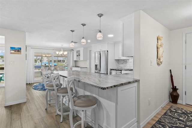 4252 Floramar Ter, New Port Richey, FL 34652 - kitchen with stainless steel appliances, light wood-style flooring, white cabinets, a peninsula, and a chandelier