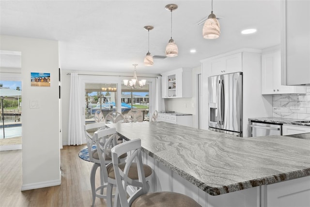 4252 Floramar Ter, New Port Richey, FL 34652 - kitchen with stainless steel appliances, white cabinets, light wood-style floors, a chandelier, and stone counters