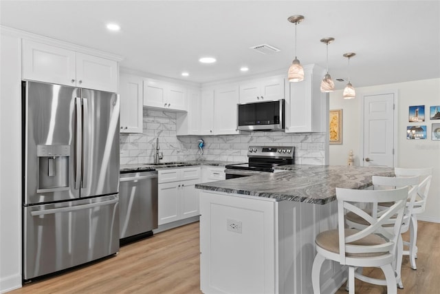 4252 Floramar Ter, New Port Richey, FL 34652 - kitchen featuring stainless steel appliances, light wood finished floors, a peninsula, white cabinetry, and recessed lighting