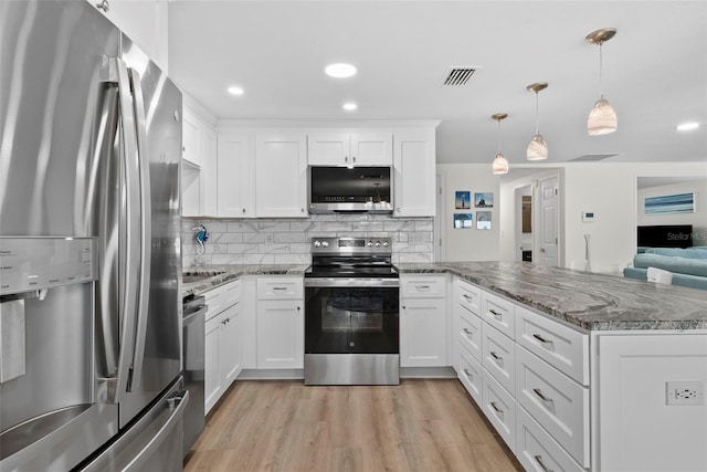 4252 Floramar Ter, New Port Richey, FL 34652 - kitchen featuring appliances with stainless steel finishes, a peninsula, white cabinetry, light wood-style flooring, and decorative backsplash