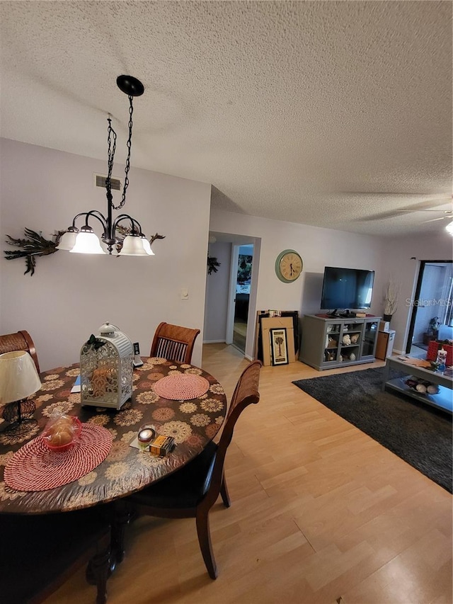 2685 Sabal Springs Cir Unit 202, Clearwater, FL 33761 - dining space featuring a textured ceiling, light wood-style flooring, and a chandelier