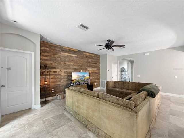 4079 Pacente Loop, Wesley Chapel, FL 33543 - living room with wood walls, arched walkways, ceiling fan, an accent wall, and a multi sided fireplace
