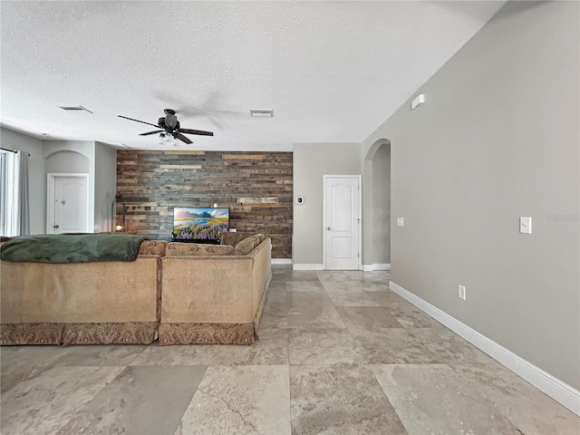 4079 Pacente Loop, Wesley Chapel, FL 33543 - living room with a ceiling fan, arched walkways, wood walls, a textured ceiling, and an accent wall