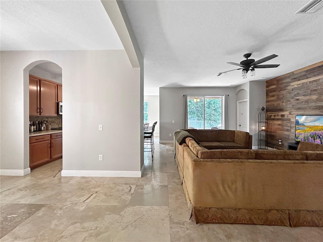 4079 Pacente Loop, Wesley Chapel, FL 33543 - living area featuring a textured ceiling, a ceiling fan, wood walls, and arched walkways