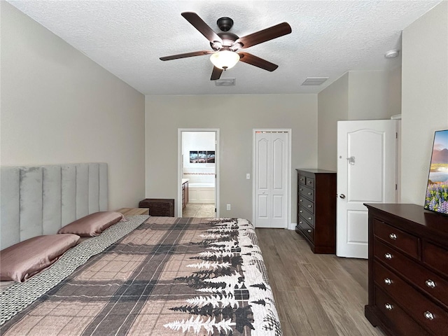 4079 Pacente Loop, Wesley Chapel, FL 33543 - bedroom with wood finished floors, a textured ceiling, connected bathroom, a ceiling fan, and a closet