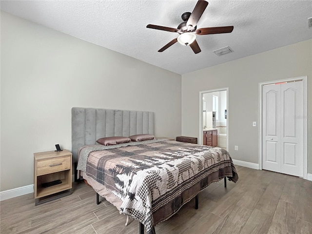 4079 Pacente Loop, Wesley Chapel, FL 33543 - bedroom featuring light wood-style floors, ensuite bath, a textured ceiling, and a ceiling fan