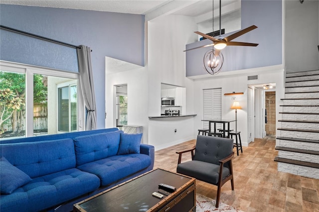 2095 Sunset Point Rd Unit 2201, Clearwater, FL 33765 - living room with high vaulted ceiling, stairs, a ceiling fan, and light wood-style flooring