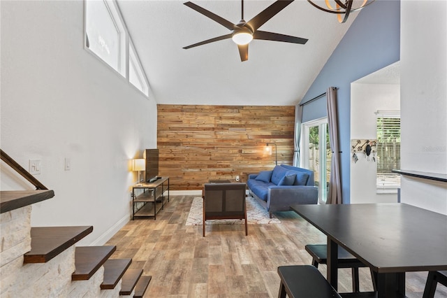 2095 Sunset Point Rd Unit 2201, Clearwater, FL 33765 - living room featuring high vaulted ceiling, wooden walls, ceiling fan, light wood-type flooring, and an accent wall