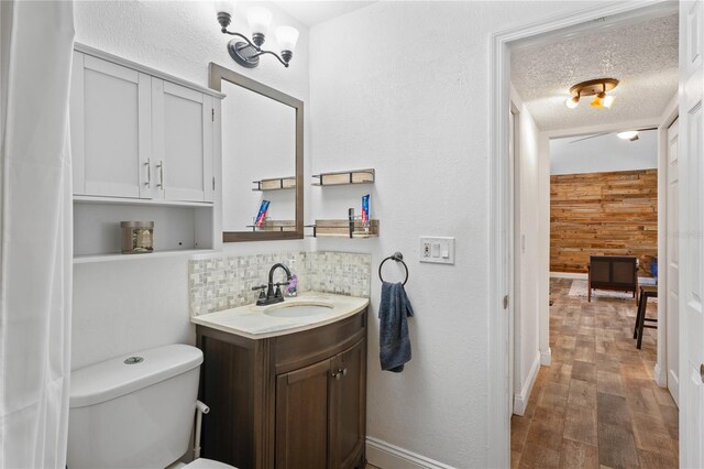 2095 Sunset Point Rd Unit 2201, Clearwater, FL 33765 - bathroom with vanity, wood walls, decorative backsplash, wood finished floors, and a textured ceiling