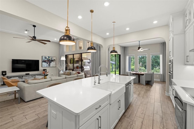 2839 Cordoba Ranch Blvd, Lutz, FL 33559 - kitchen with a ceiling fan, a center island with sink, light wood-style floors, arched walkways, and recessed lighting