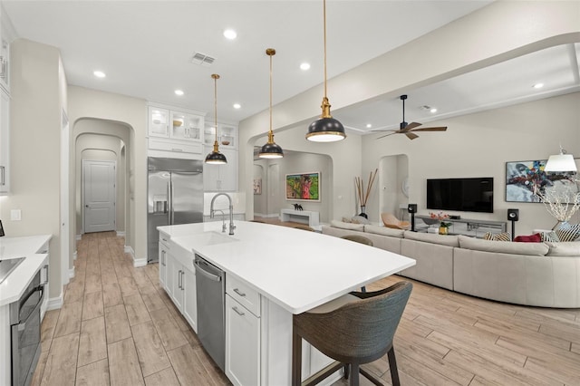 2839 Cordoba Ranch Blvd, Lutz, FL 33559 - kitchen with arched walkways, stainless steel appliances, light wood-type flooring, white cabinetry, and recessed lighting