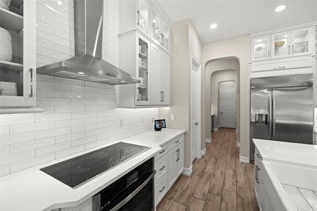 2839 Cordoba Ranch Blvd, Lutz, FL 33559 - kitchen with wall chimney exhaust hood, black appliances, arched walkways, dark wood-style floors, and decorative backsplash
