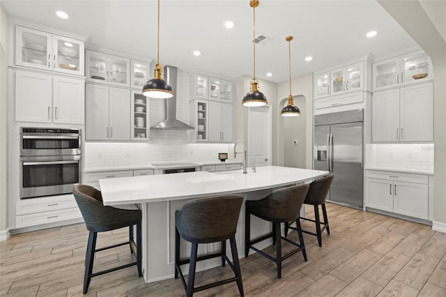 2839 Cordoba Ranch Blvd, Lutz, FL 33559 - kitchen with stainless steel appliances, wall chimney exhaust hood, backsplash, light countertops, and light wood-type flooring