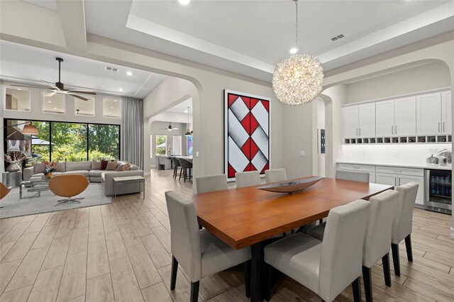 2839 Cordoba Ranch Blvd, Lutz, FL 33559 - dining room featuring arched walkways, wine cooler, light wood-style floors, a raised ceiling, and recessed lighting