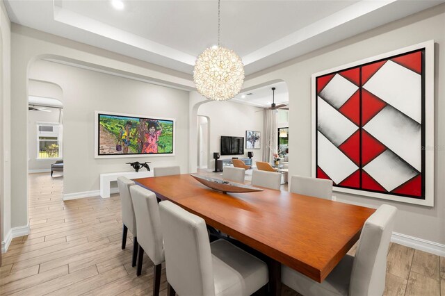 2839 Cordoba Ranch Blvd, Lutz, FL 33559 - dining area with arched walkways, ceiling fan, light wood-style floors, a raised ceiling, and healthy amount of natural light