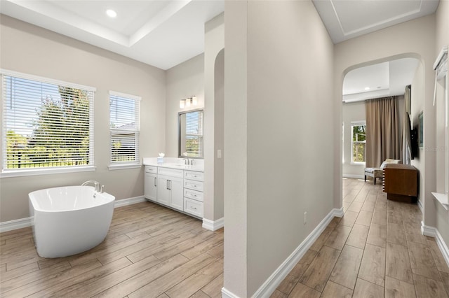 2839 Cordoba Ranch Blvd, Lutz, FL 33559 - full bathroom featuring vanity, wood finished floors, a freestanding tub, a raised ceiling, and recessed lighting