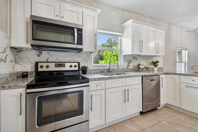 2812 Tom Brewer Ln, Plant City, FL 33566 - kitchen with appliances with stainless steel finishes, white cabinetry, backsplash, light tile patterned flooring, and light stone counters