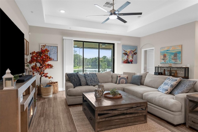 11597 Weaver Hollow Rd, New Port Richey, FL 34654 - living room featuring a raised ceiling, wood finished floors, a ceiling fan, recessed lighting, and arched walkways