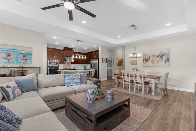 11597 Weaver Hollow Rd, New Port Richey, FL 34654 - living room featuring a chandelier, light wood finished floors, a ceiling fan, recessed lighting, and a raised ceiling
