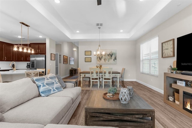 11597 Weaver Hollow Rd, New Port Richey, FL 34654 - living room featuring recessed lighting, light wood-style floors, a chandelier, and a tray ceiling