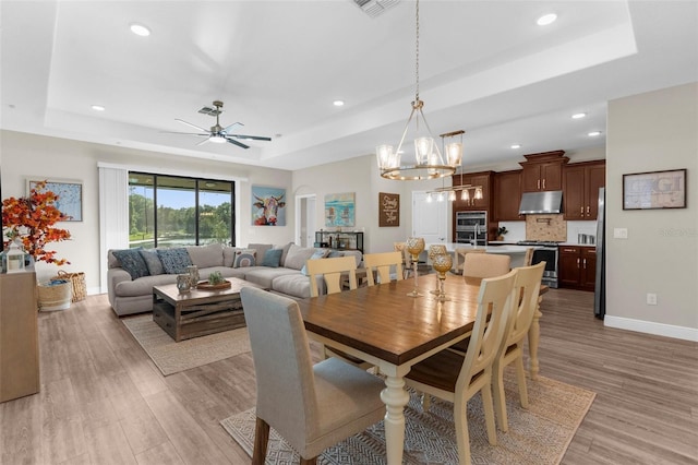 11597 Weaver Hollow Rd, New Port Richey, FL 34654 - dining space with a raised ceiling, light wood finished floors, recessed lighting, ceiling fan, and a chandelier
